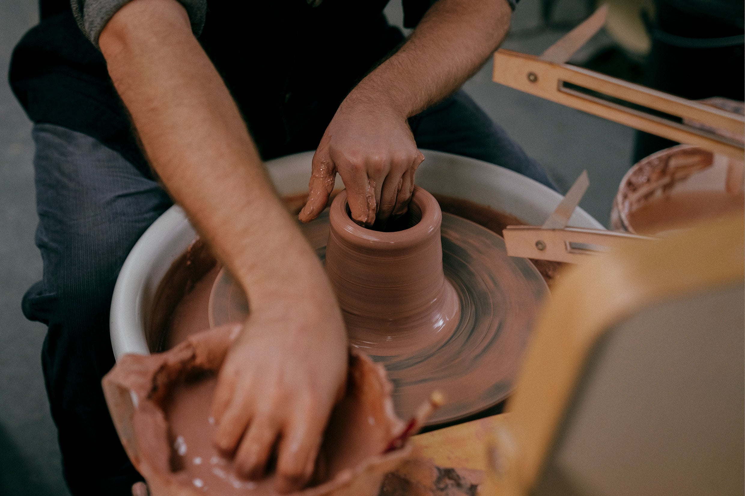 Hands throwing clay on the wheel