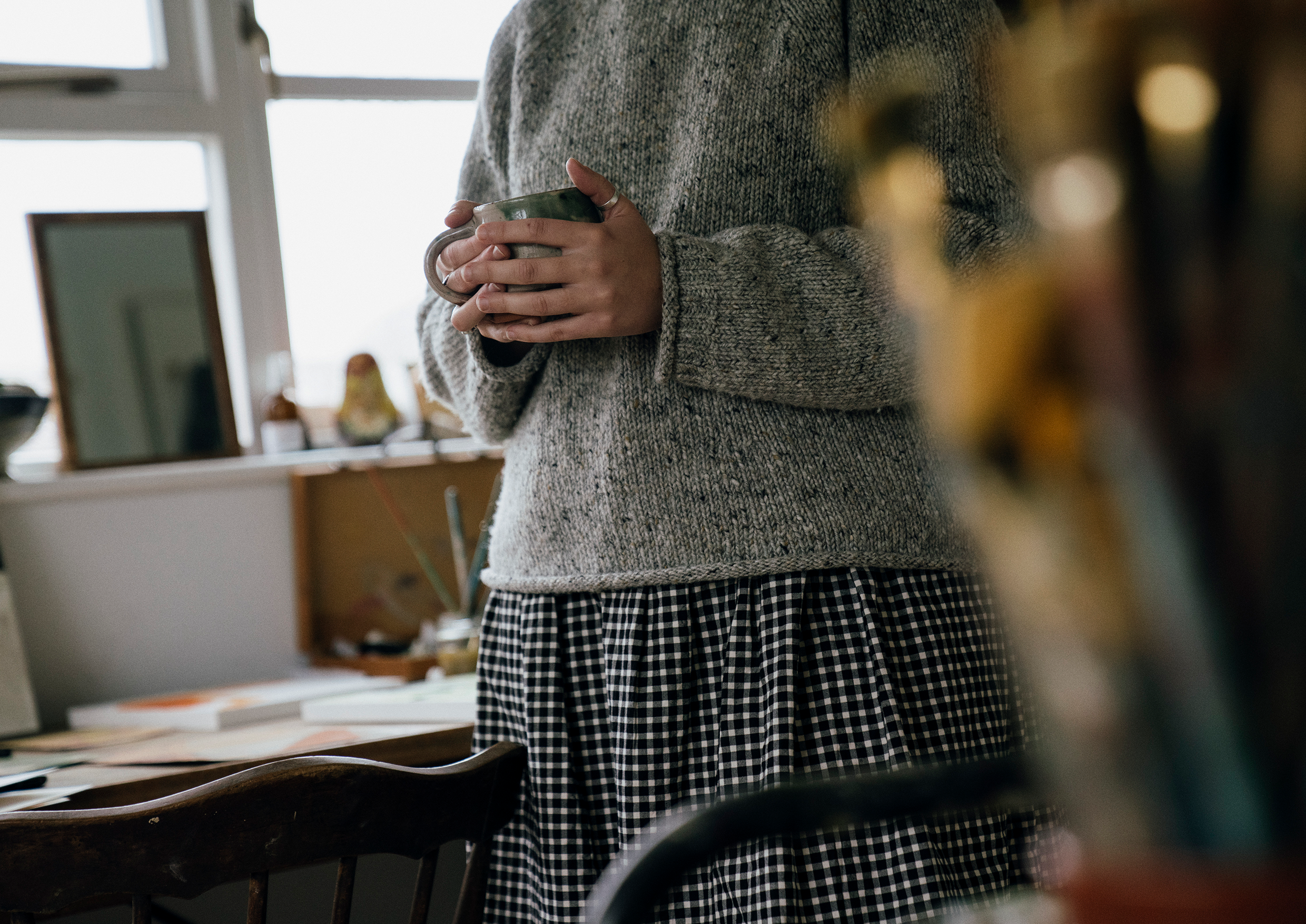 A person in a grey jumper holding a ceramic cup