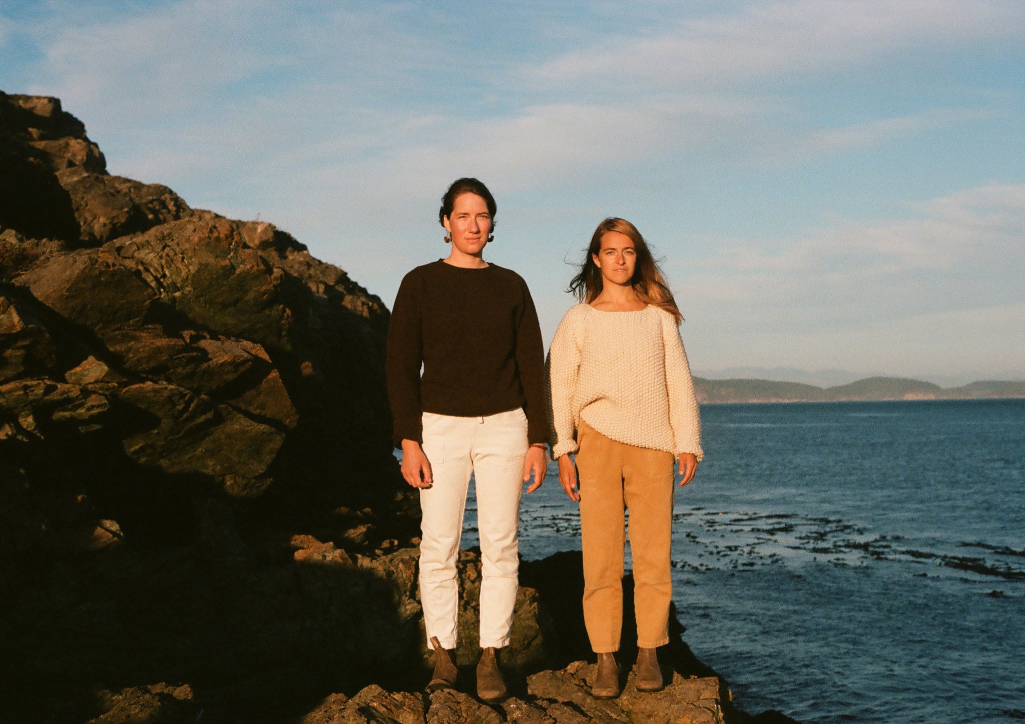 Two people standing on a rock in the sea
