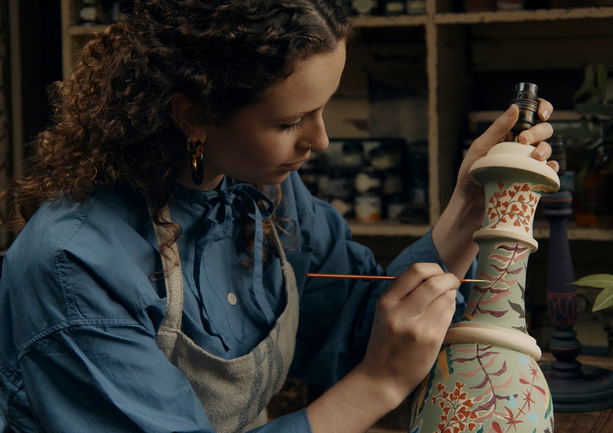 Woman painting a lamp.