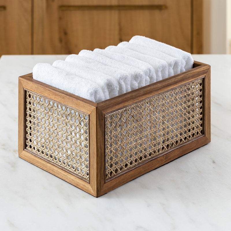 rattan and acacia wood organizing basket holding white hand towels