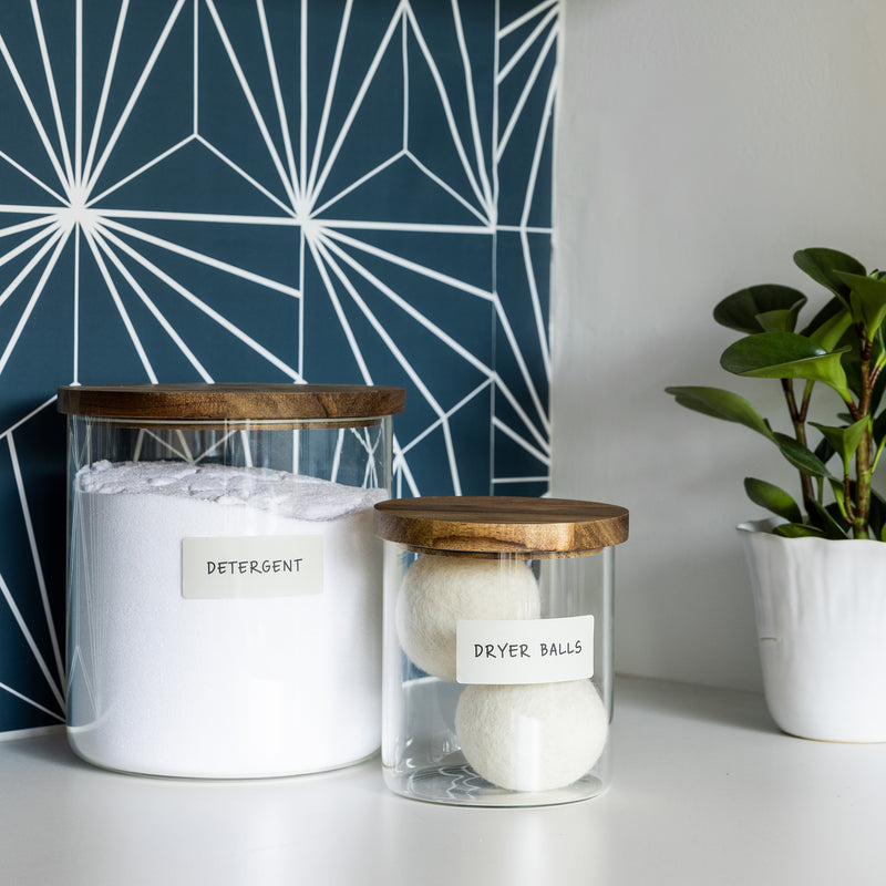 glass jars holding laundry detergent and dryer balls with white removable labels