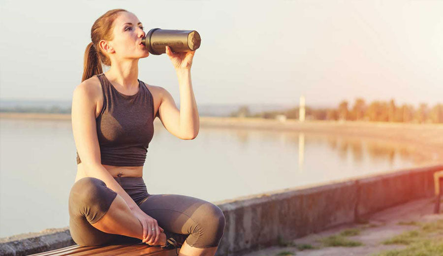 Mujer bebiendo proteína hidrolizada después de rutina de ejercicio