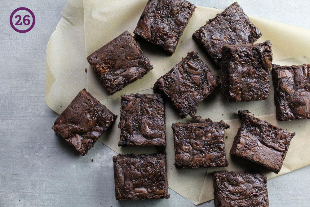 Brownies laid out on a gray table on top of parchment paper. The image is labeled "26" in the upper left corner.