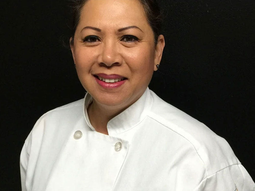 A woman with a white chef's shirt against a black backdrop