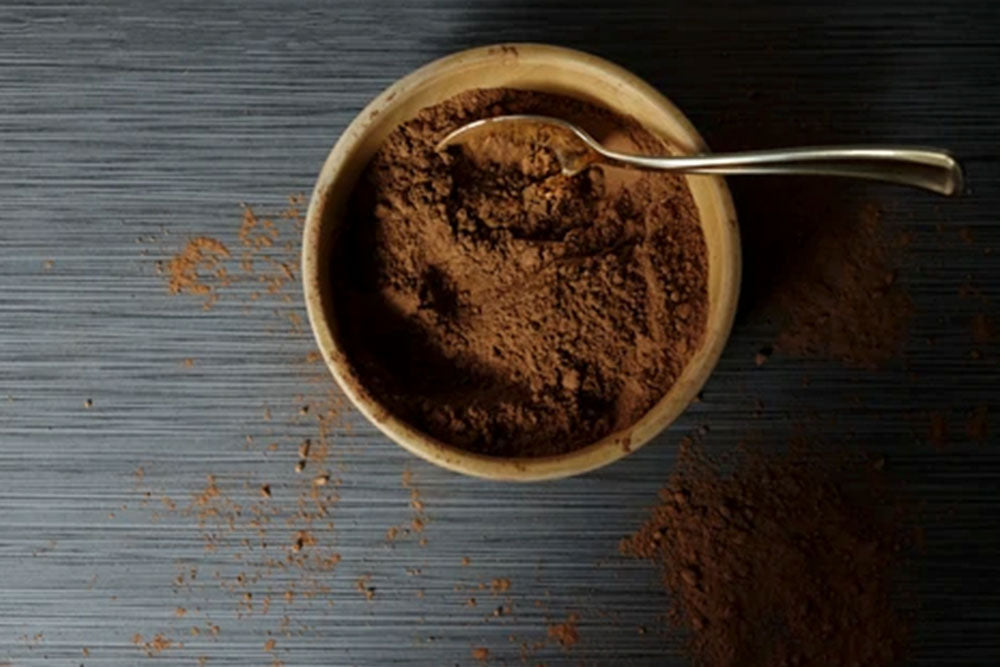 A small bowl of cocoa powder on a dark gray table. 