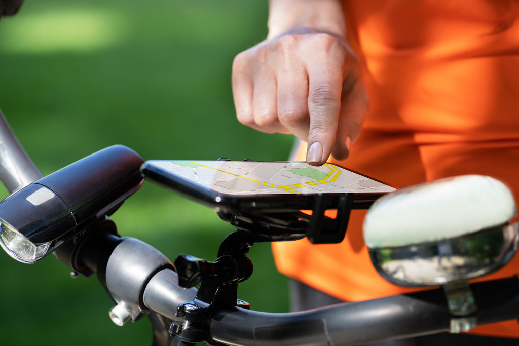 User tapping a phone on a bike handlebar using a self guided navigation app on 