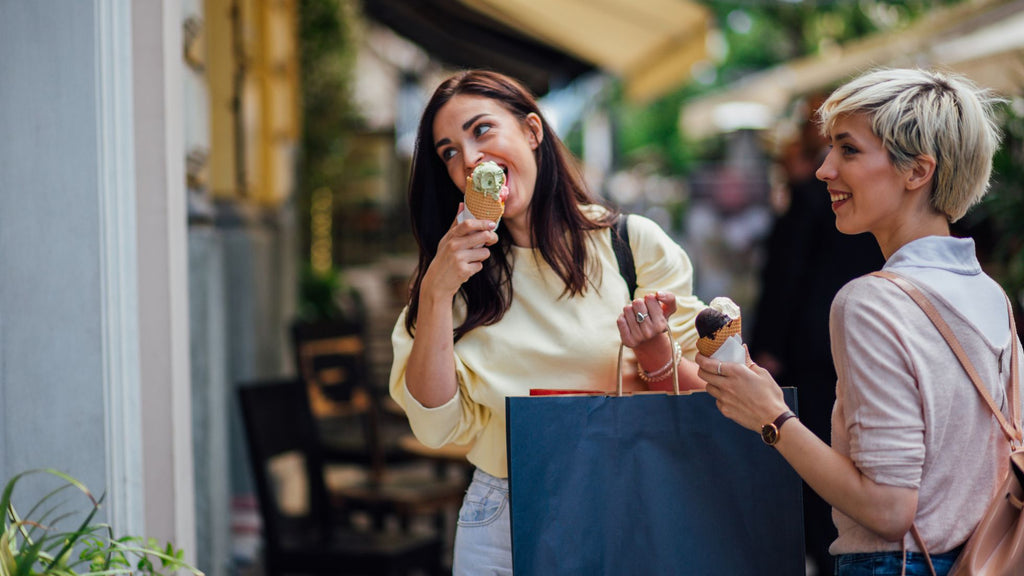 Two young ladies eating icecream outside a shop on a shopping tour