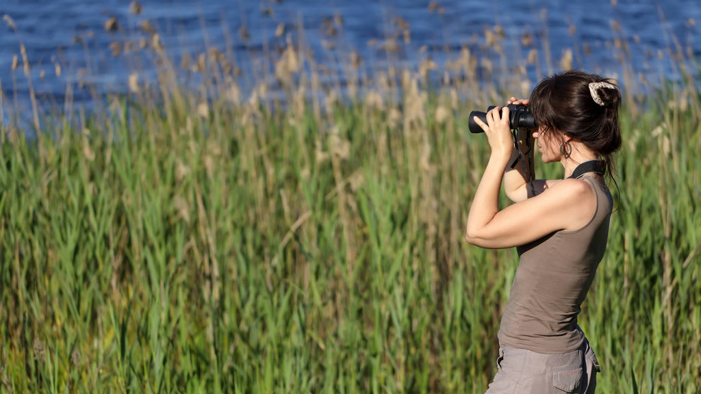 Young woman using binoculars to view wildlife on a self guided outdoor tour