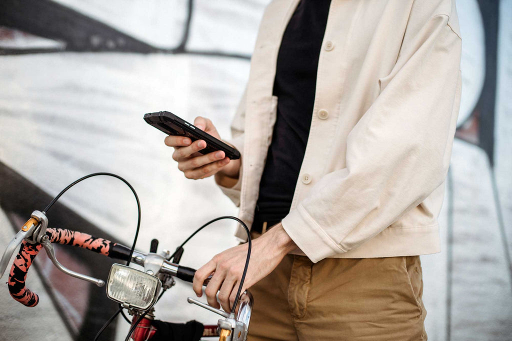 Man uses his mobile phone to view a navigation route while holding the handlebar of his bicycle