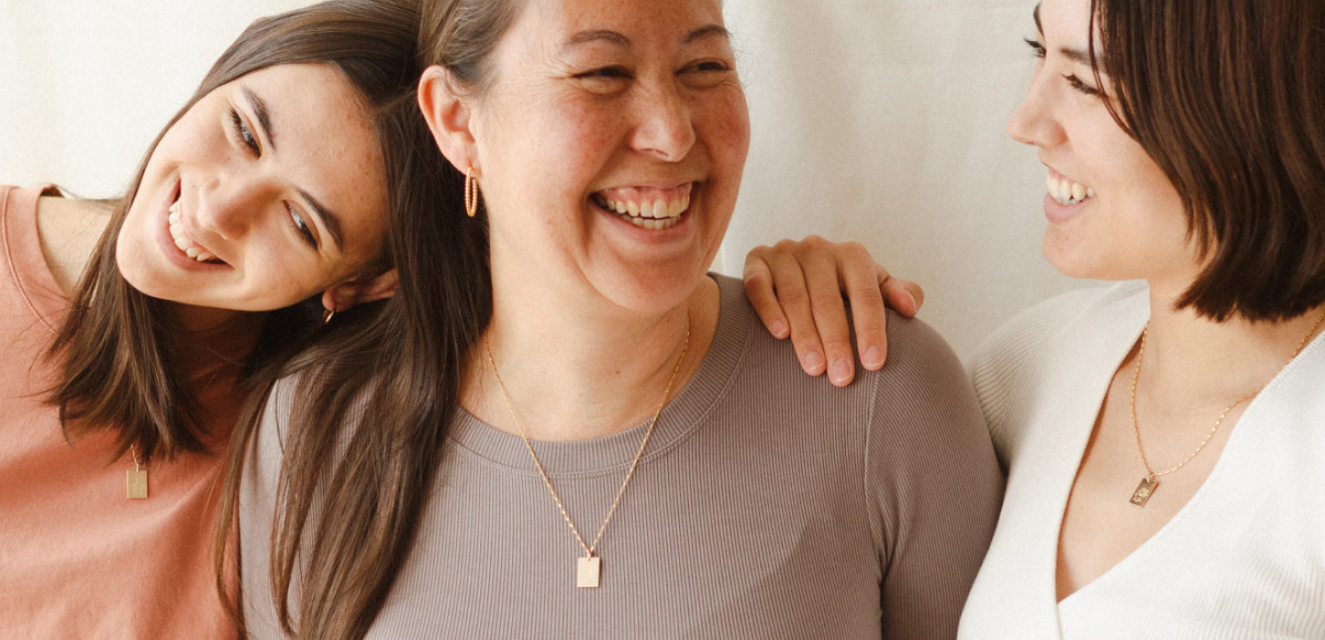 Mom and daughters posing with personalized necklaces