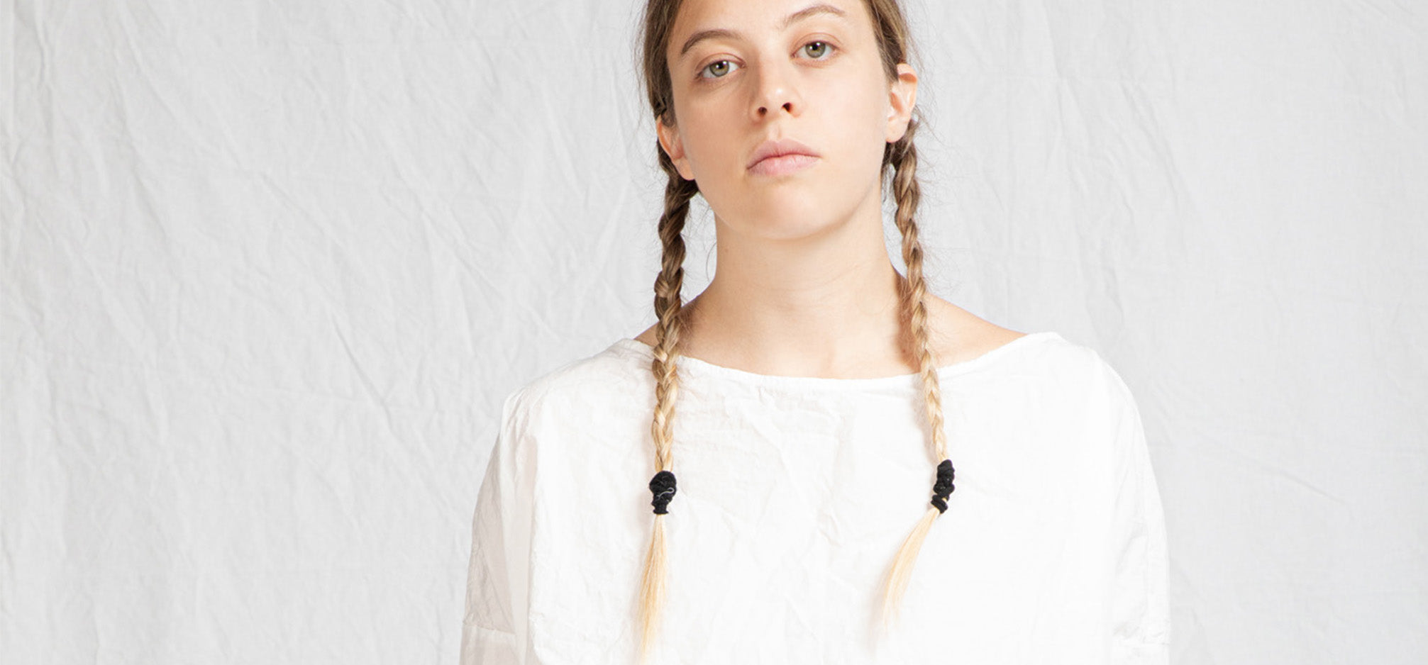 Image of girl with two plaits in her hair wearing a white cotton top