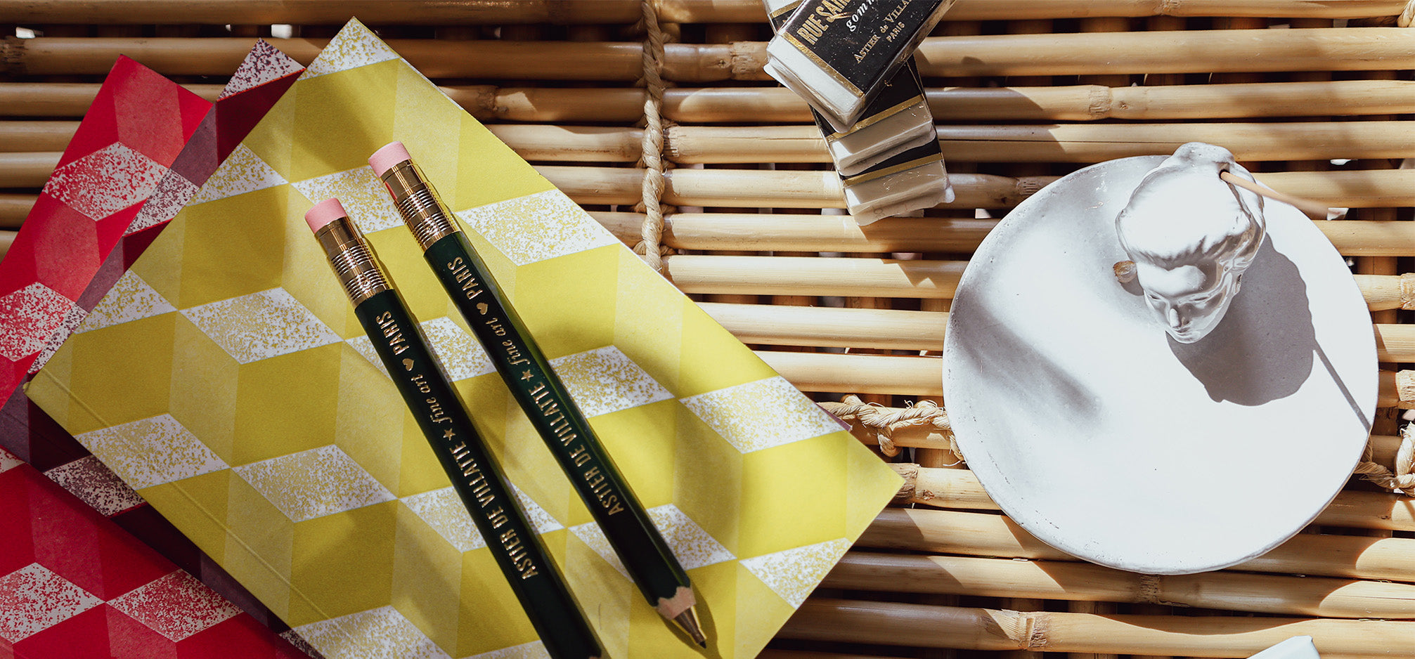 Astier De Village note books, mechanical pencil, erasers and incense on a table