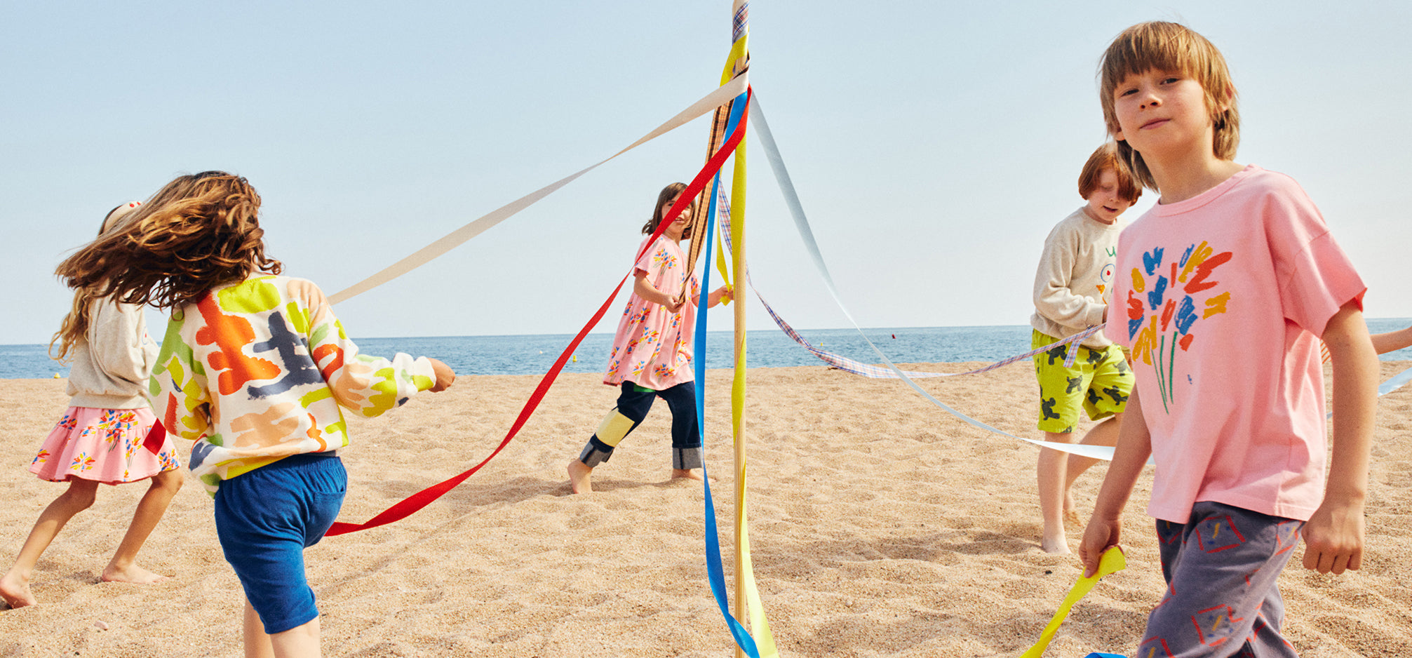 Children at the beach playing around a Maypole