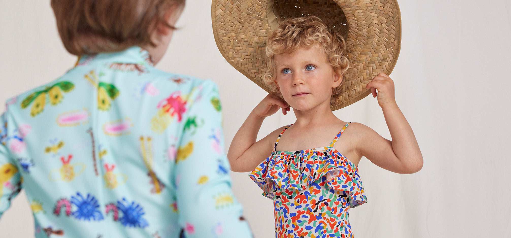 Child wearing straw hat and bobo choses swimsuit