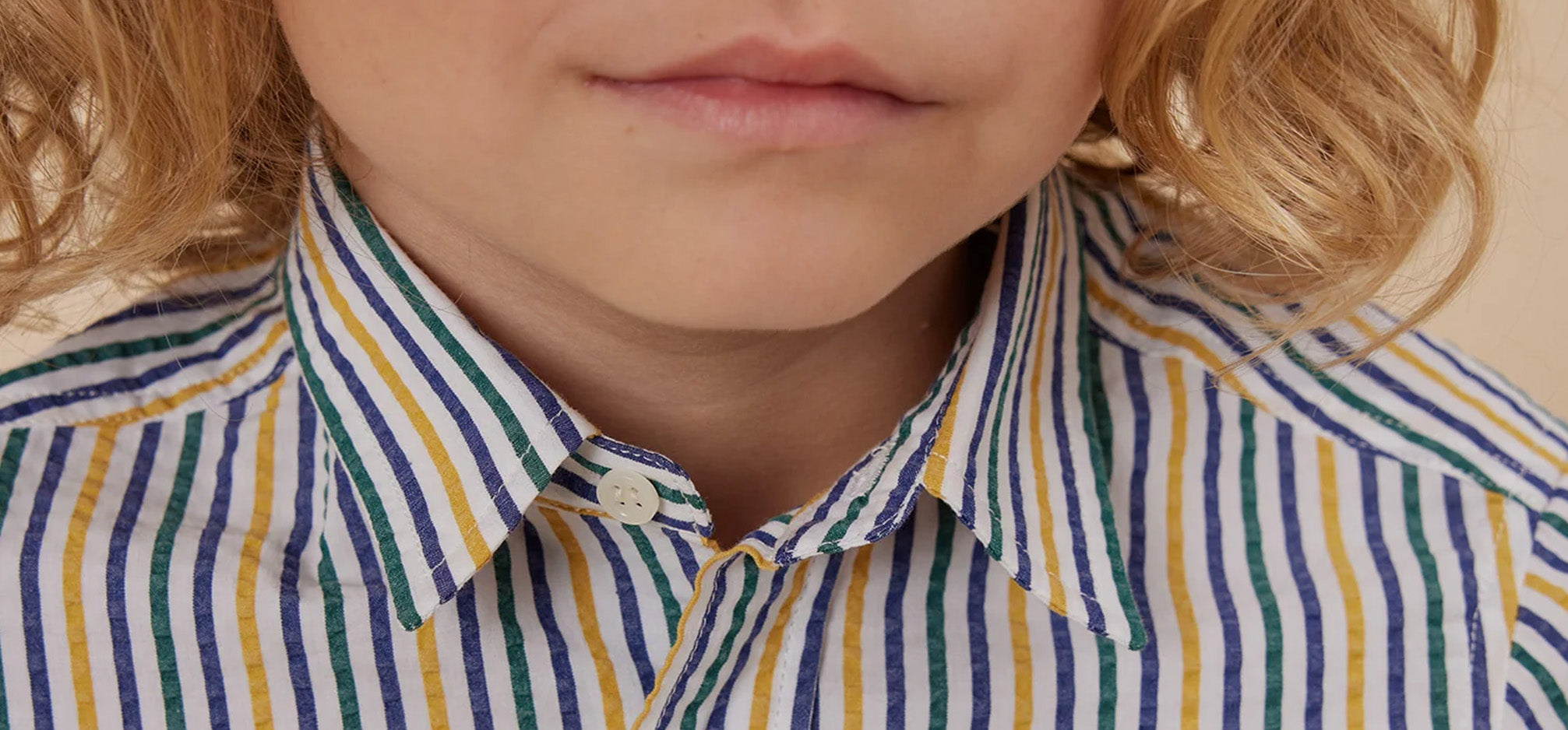 Image of child wearing a blue, green and yellow collared shirt