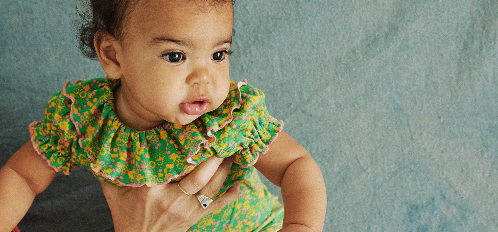 Baby wearing Misha & Puff green floral top with ruffle collar