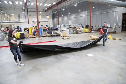 USCC team members move folded custom tarp across concrete warehouse floor for further inspection