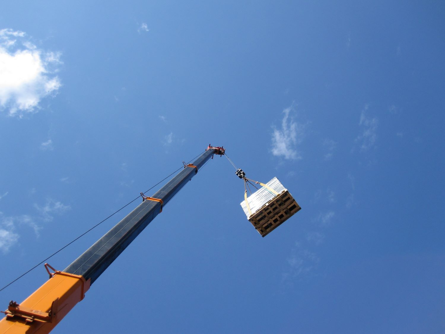 crane hoisting up a pallet using snatch block and wire rope cables