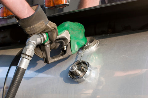 truck driver at pump filling up semi truck with diesel fuel