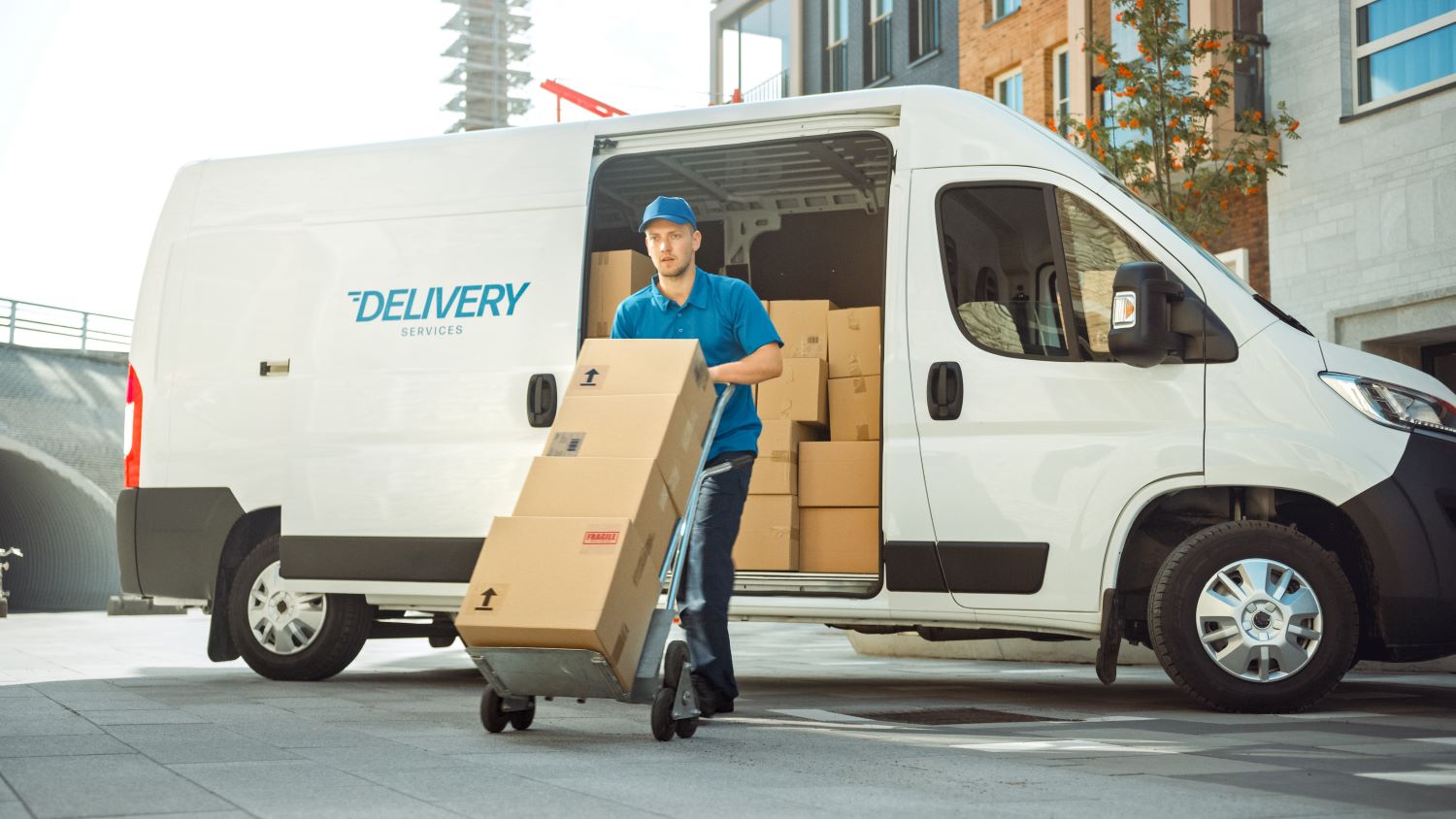 delivery van with driver hauling boxed cargo on hand truck