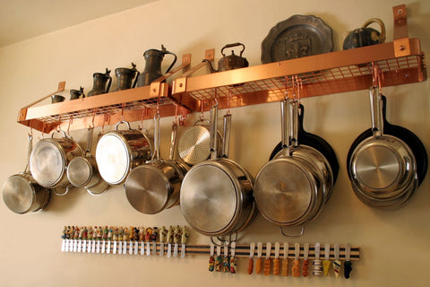 hanging pots and pans by hooks along kitchen wall