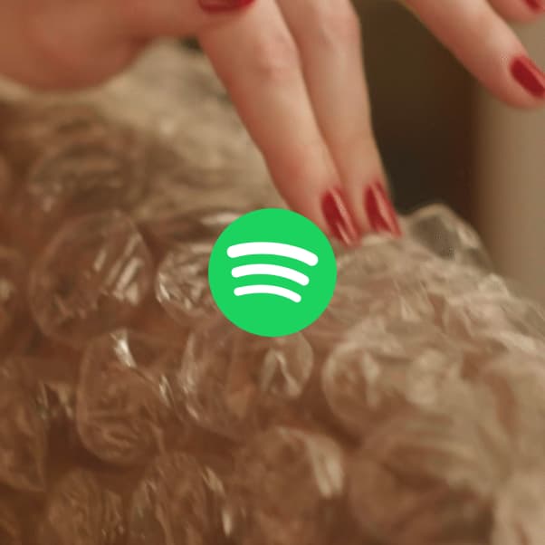 Hand popping bubble wrap, with a Spotify logo overlay.