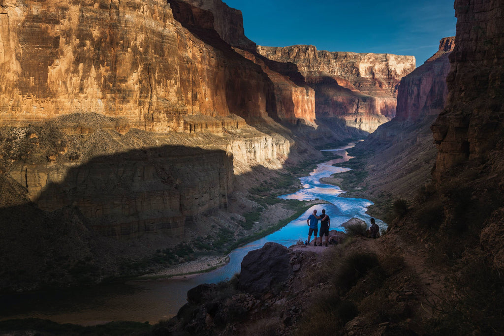 two person standing on rocks facing body of water photo