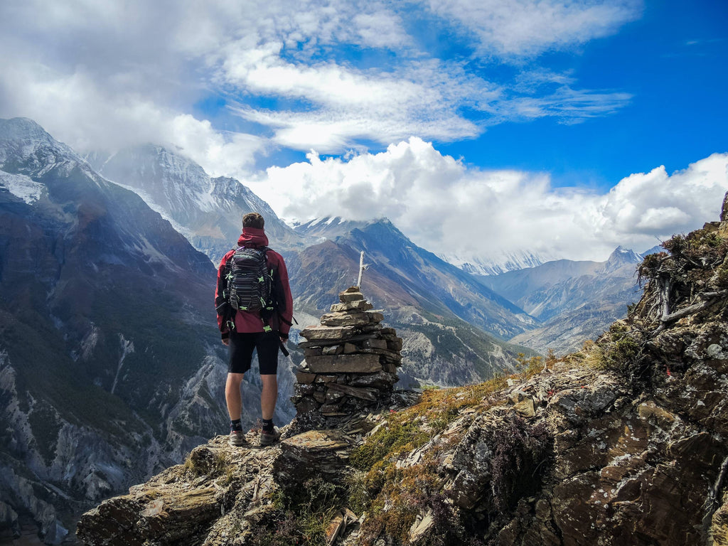 man standing on top of mountain beside cairn stones photo