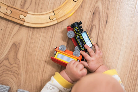 Baby playing on the floor with trains