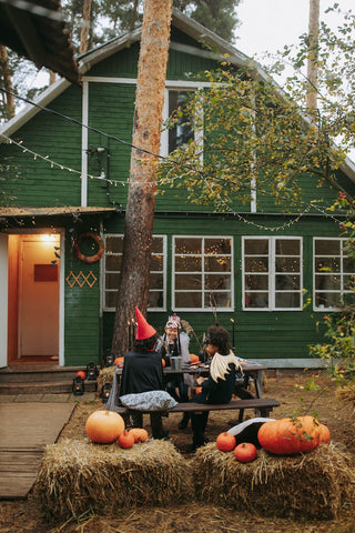 Children sitting on picnic bench in front of house dressed in Halloween costumes