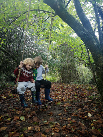 Alfie and Finley on a swing in the woods