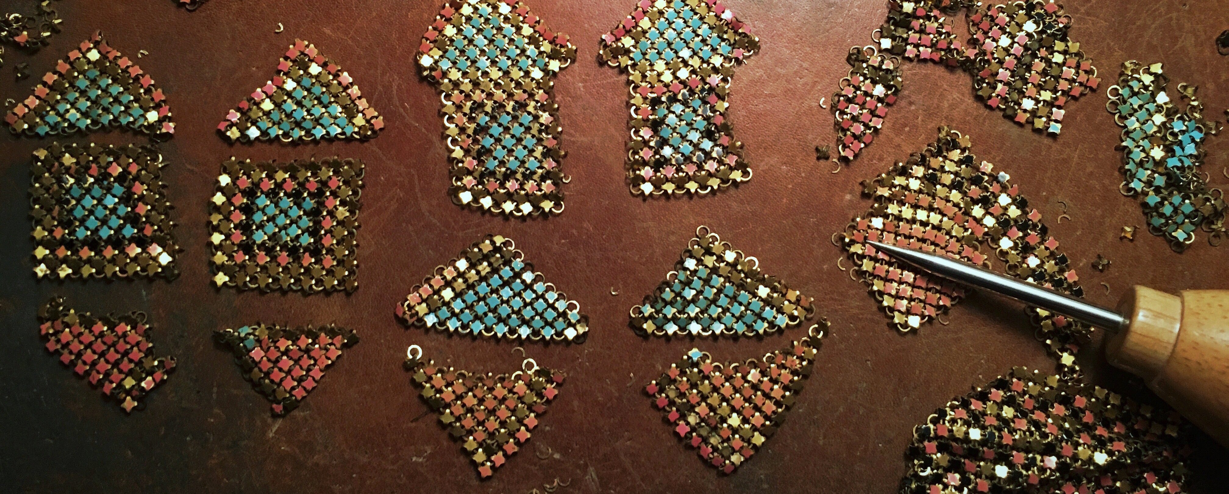 Process shot of antique metal mesh being pieced into earring forms.