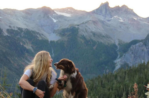 Dog and woman sitting in front of a mountain in Whistler