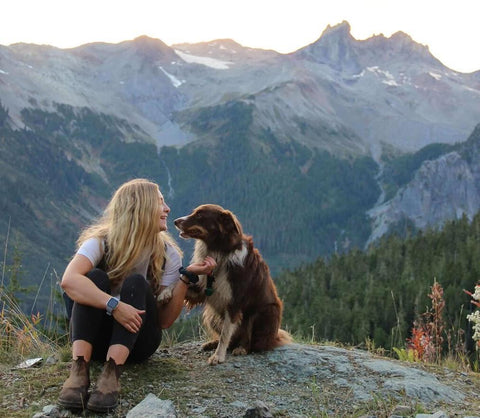 Woman and dog sitting in the mountains