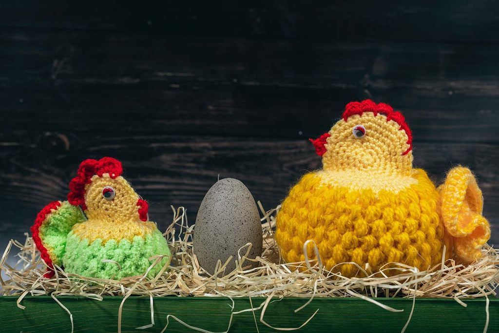 Knitted hens sitting on nest of eggs.