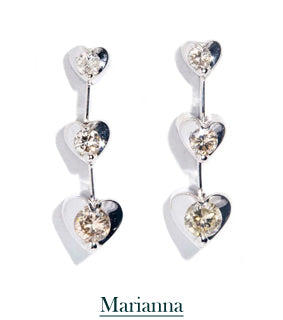 A pair of drop earrings - each pair has three white gold shaped hearts with a diamond centre