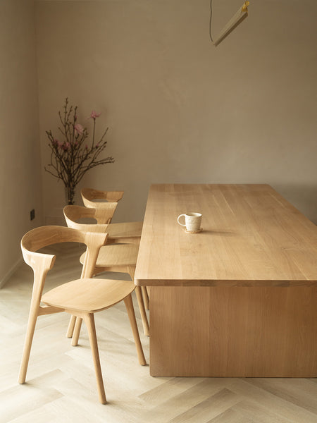 Wooden scandi dining interior with minimalist linear pendant Ando chandelier in brass