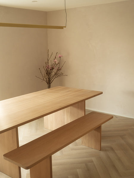 Wooden scandi dining interior with minimalist linear pendant Ando chandelier in brass