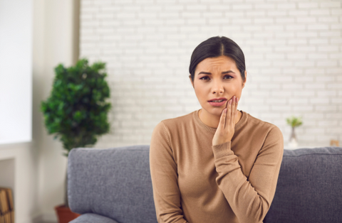 woman holding her cheek due to toothache and sensitivity