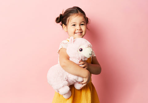 Child hugging a llama stuffed animal for comfort.