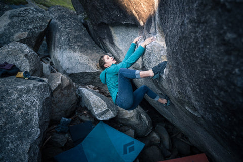 Woman climbing outdoors on a large boulder.