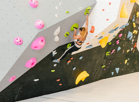Woman bouldering inside at a climbing gym
