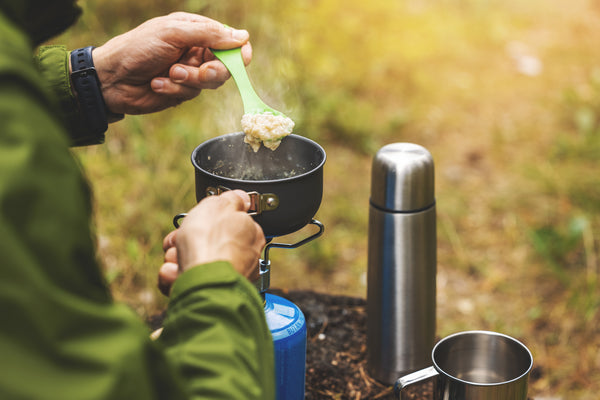 man cooking oatmeal on camping stove