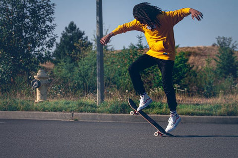 a boy with yellow shirt skating on road