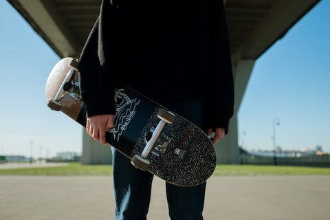 a person holding skateboard under a bridge