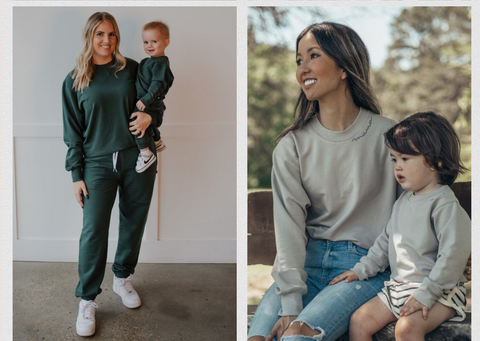 Woman stands holding her child wearing matching loungewear. The word Mama is embroidered on the neck of the sweater 