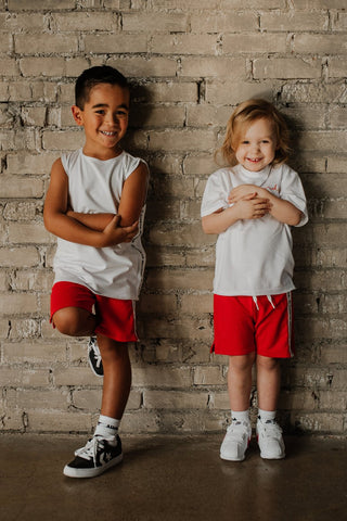 Kids canadian made sustainable clothing being modeled. Red shorts and white tank made by North Kinder.