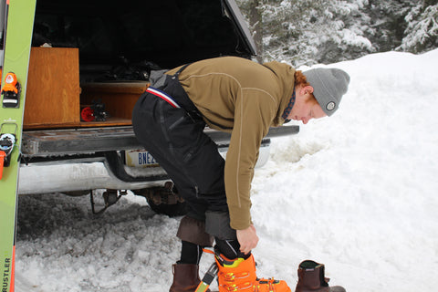 Ben Goertzen putting on ski boots, while wearing Jelt's USA belt