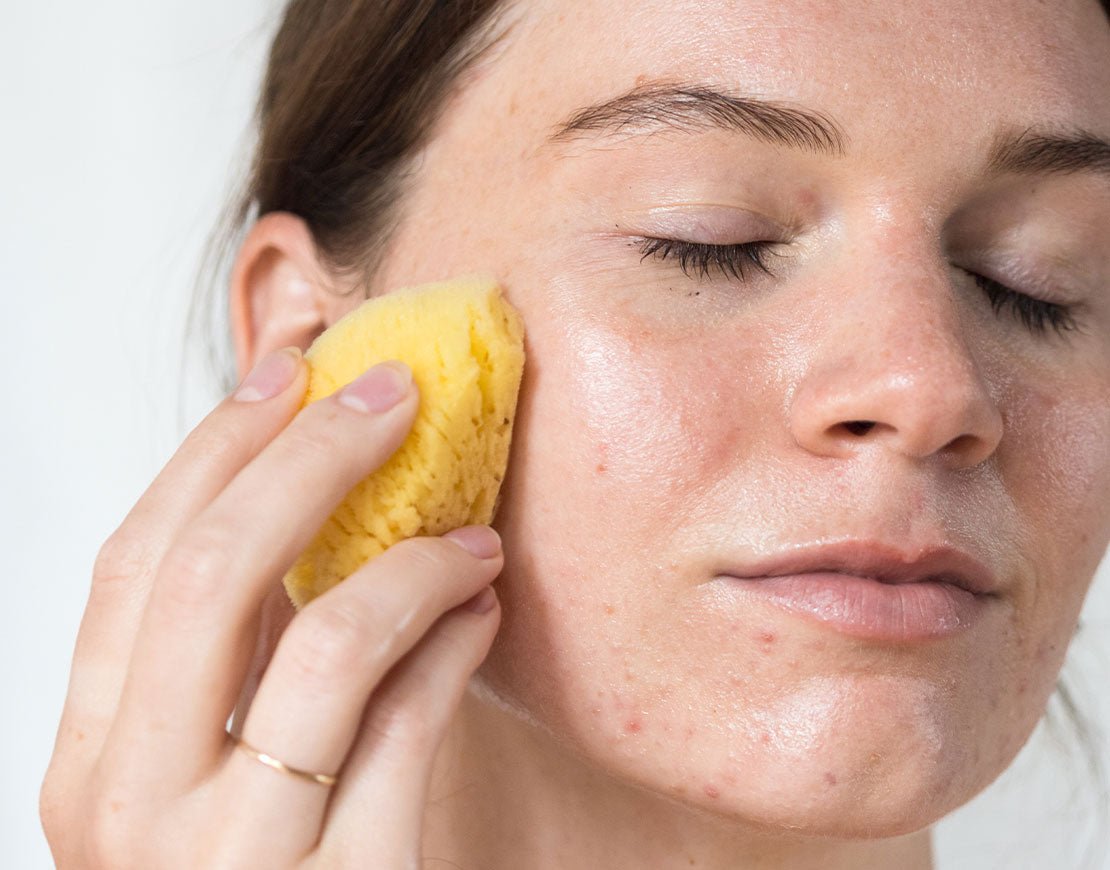 Person exfoliating their face with a sea sponge